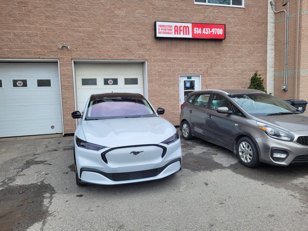  Carrossier ponçant un panneau de carrosserie dans un atelier à Dollard-des-Ormeaux 
