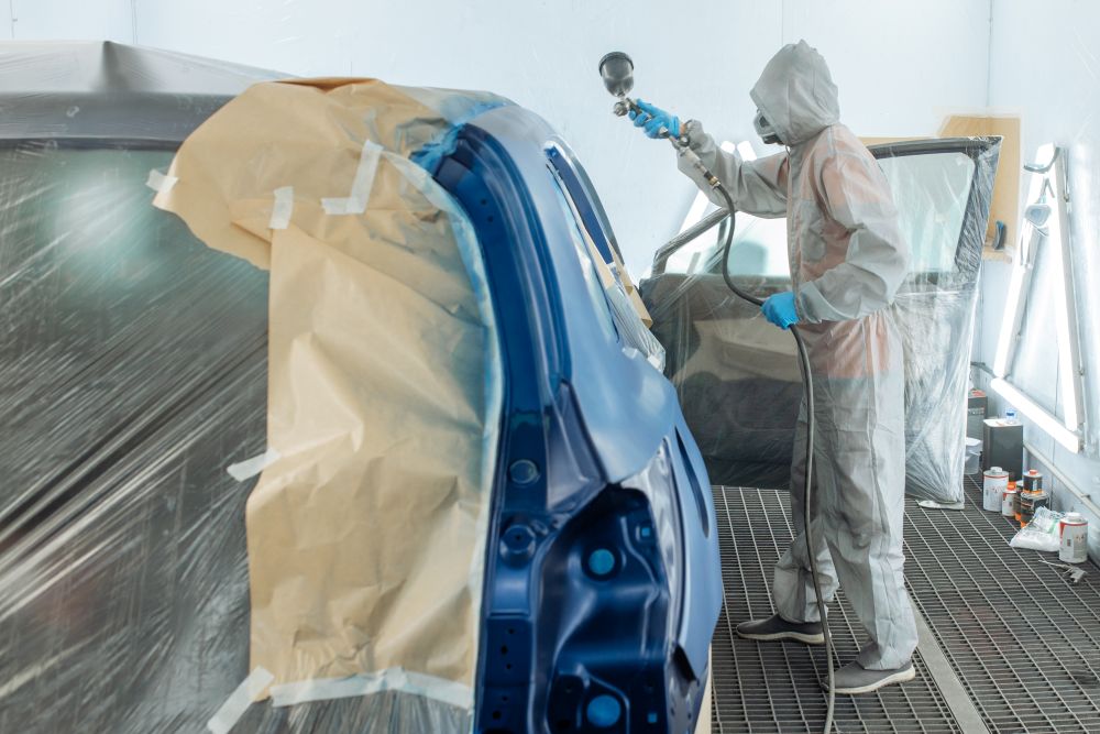  Carrossier ponçant un panneau de carrosserie dans un atelier à Drummondville 
