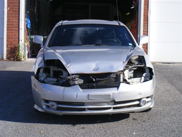 Panneaux et pare‑chocs en attente de réparation dans un atelier de carrosserie à La Prairie 